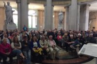 Audience seated in museum rotunda with statues