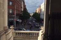 View down urban street from stone building steps
