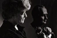 Woman examining small sculpture, bust in background