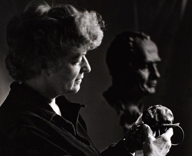 Woman examining small sculpture, bust in background